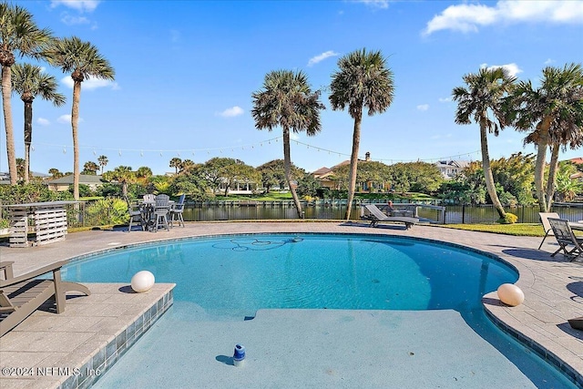 view of swimming pool with a patio area and a water view