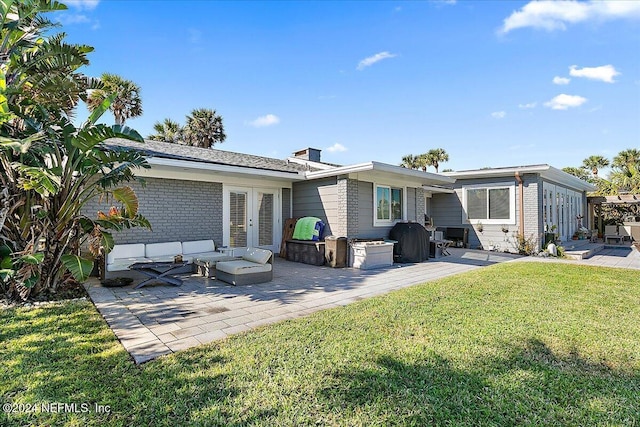 back of property with french doors, an outdoor living space, a patio area, and a yard