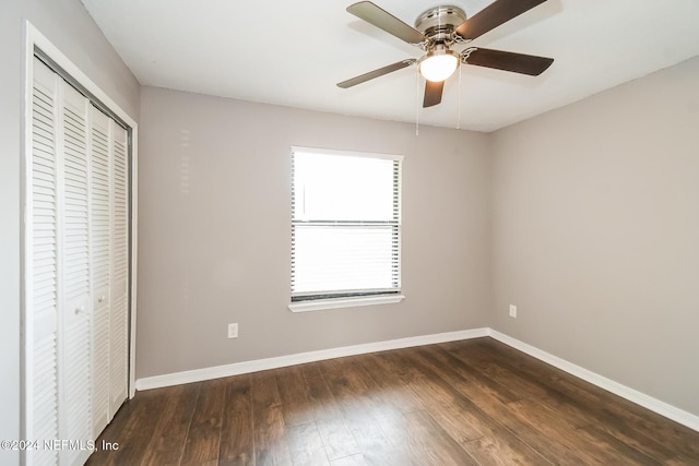 unfurnished bedroom featuring ceiling fan, a closet, and dark wood-type flooring