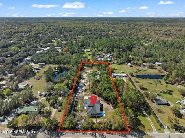 birds eye view of property featuring a forest view and a water view