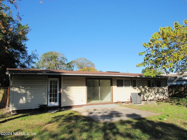 rear view of house featuring central AC unit and a yard