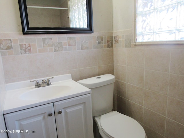 bathroom featuring vanity, toilet, and tile walls