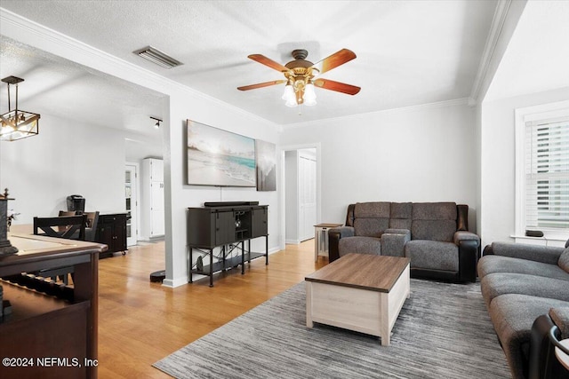 living room with crown molding, ceiling fan, wood-type flooring, and a textured ceiling