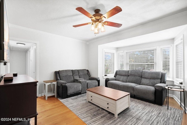 living room with a textured ceiling, light hardwood / wood-style floors, ceiling fan, and ornamental molding