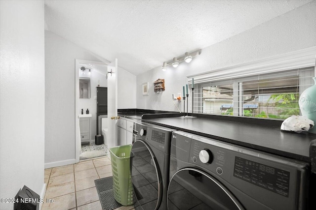 laundry area with independent washer and dryer, a textured ceiling, and light tile patterned floors