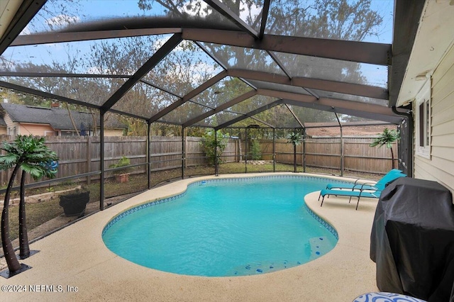 view of swimming pool featuring glass enclosure, a patio area, and grilling area