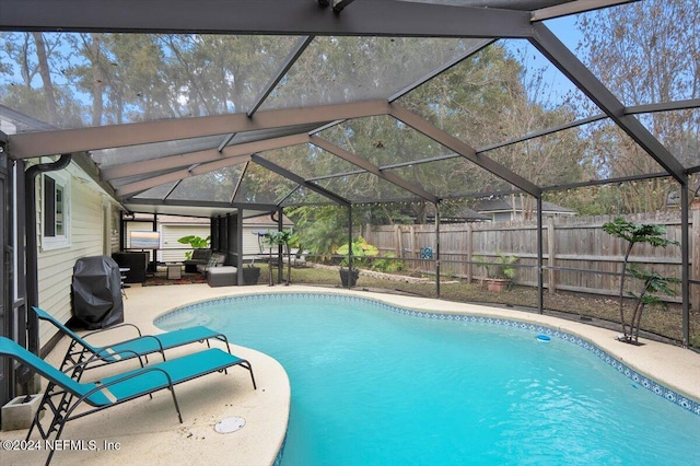 view of swimming pool with a patio, glass enclosure, and a grill