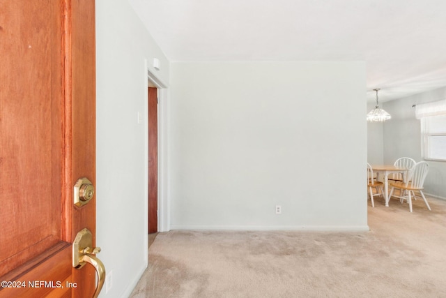 carpeted empty room featuring a notable chandelier