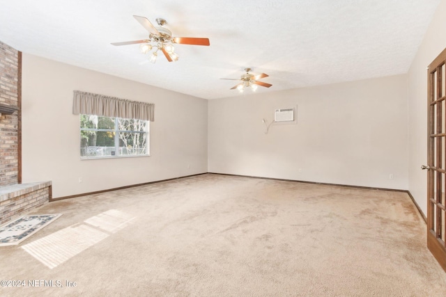 unfurnished living room featuring ceiling fan, a brick fireplace, an AC wall unit, light colored carpet, and a textured ceiling