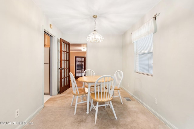 carpeted dining space with a notable chandelier