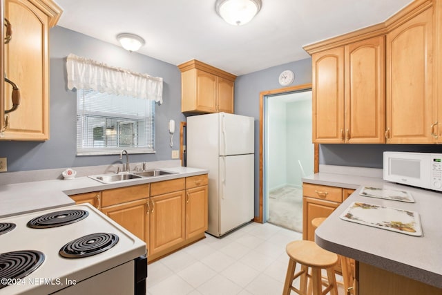 kitchen with a breakfast bar, light brown cabinets, white appliances, and sink