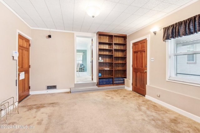 unfurnished living room with ornamental molding and light carpet