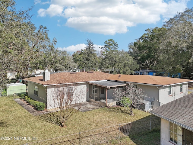 back of house featuring a lawn and a sunroom