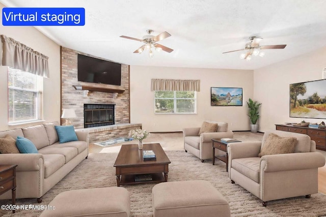 living room with a fireplace, ceiling fan, and plenty of natural light