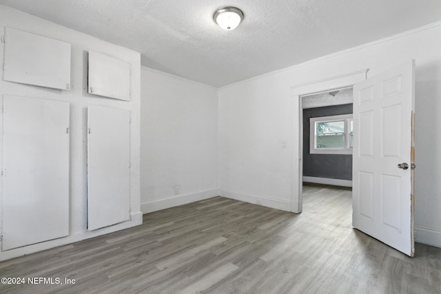 unfurnished bedroom with hardwood / wood-style floors, a textured ceiling, and ornamental molding