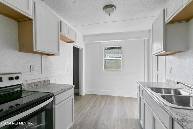 kitchen with light wood-type flooring, a textured ceiling, sink, white cabinets, and range with electric stovetop