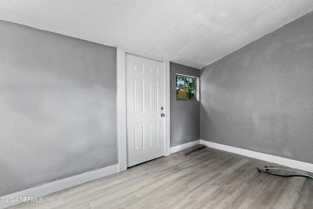 unfurnished room featuring light hardwood / wood-style floors and a textured ceiling