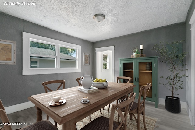 dining space featuring hardwood / wood-style floors and a textured ceiling