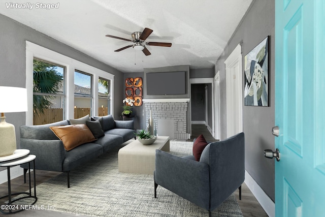 living room featuring ceiling fan, wood-type flooring, and a textured ceiling