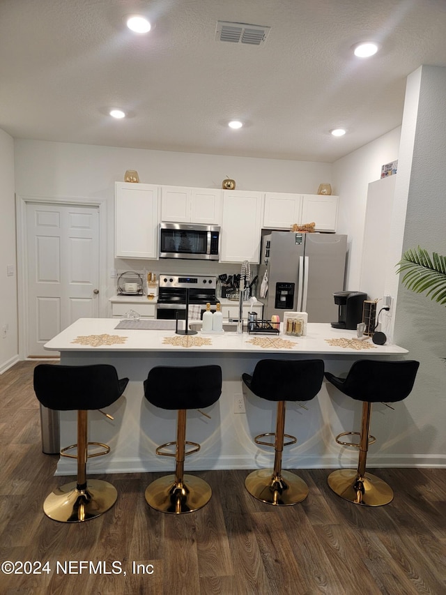 kitchen featuring white cabinetry, sink, dark wood-type flooring, stainless steel appliances, and a breakfast bar area