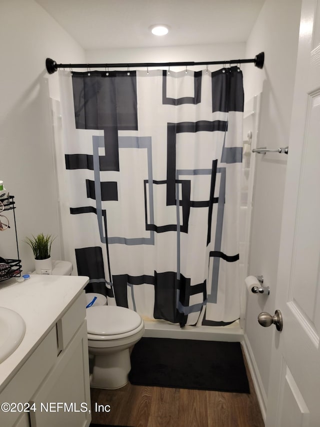 bathroom with walk in shower, hardwood / wood-style floors, vanity, and toilet