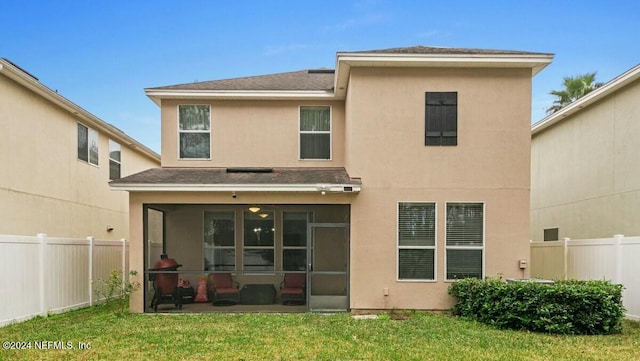 rear view of property with a sunroom and a yard