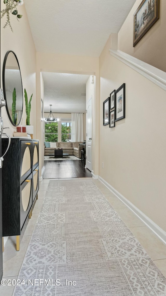 hallway featuring light tile patterned floors and a chandelier