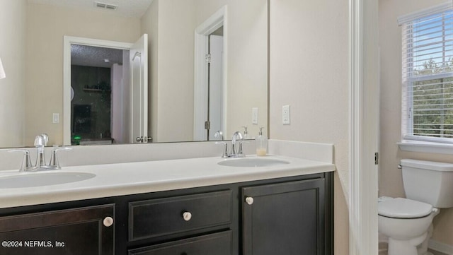 bathroom with plenty of natural light, toilet, and vanity