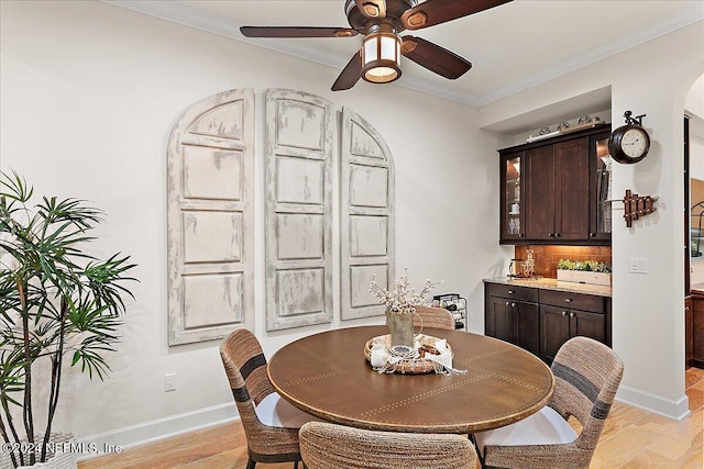 dining room with light wood-type flooring, ceiling fan, and crown molding