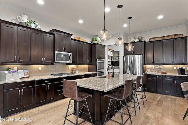 kitchen with hanging light fixtures, an island with sink, dark brown cabinets, a breakfast bar area, and stainless steel appliances