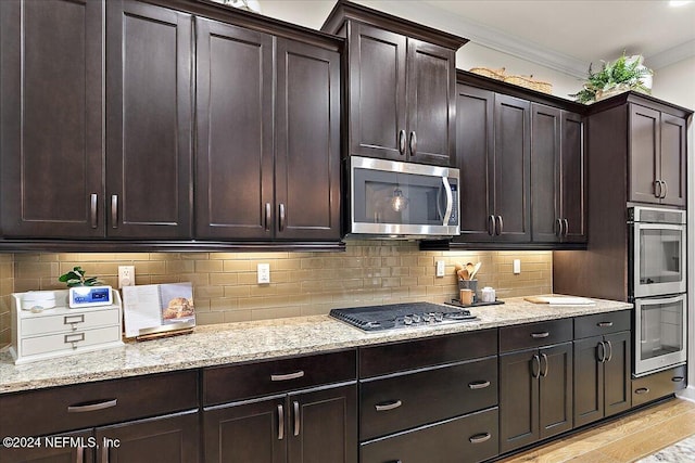 kitchen featuring appliances with stainless steel finishes, light wood-type flooring, dark brown cabinets, and crown molding