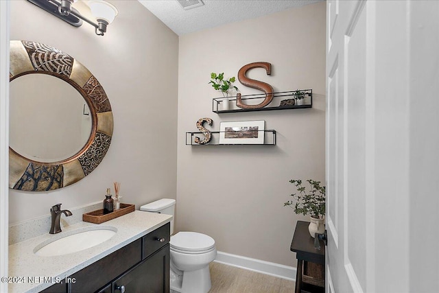 bathroom with vanity, wood-type flooring, a textured ceiling, and toilet