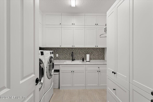 washroom featuring washer and clothes dryer, cabinets, sink, and a textured ceiling