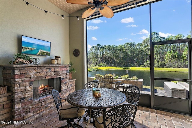 sunroom with vaulted ceiling, ceiling fan, wood ceiling, and an outdoor stone fireplace