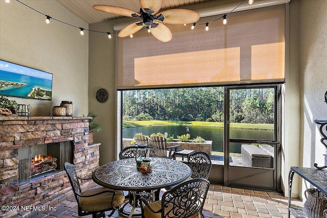 sunroom with a water view, a stone fireplace, and a healthy amount of sunlight