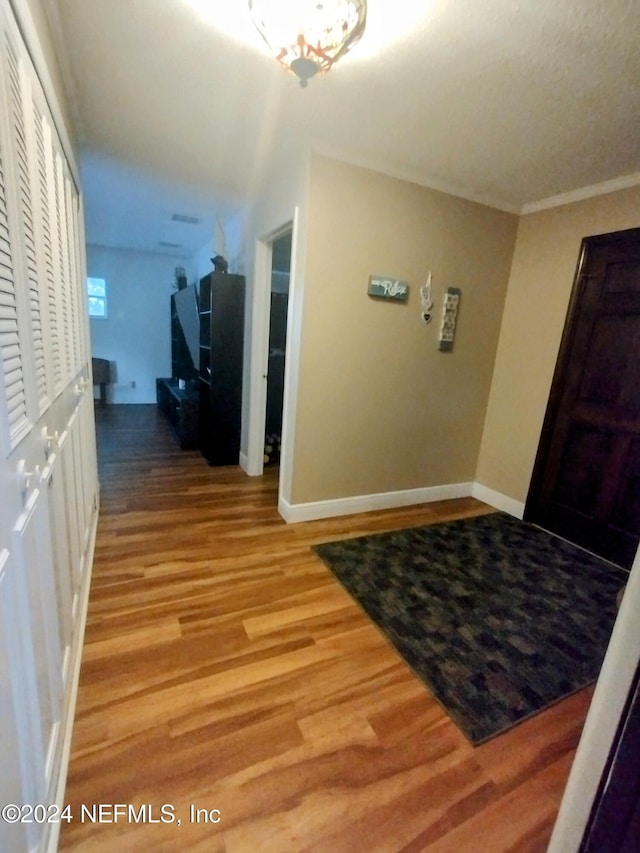 entryway with hardwood / wood-style floors and crown molding