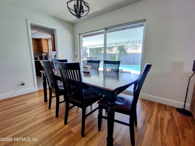 dining space with a notable chandelier, baseboards, and light wood-style floors