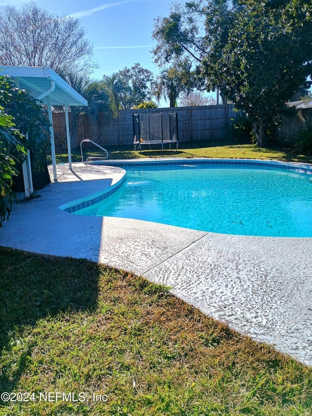 view of swimming pool featuring a yard, a trampoline, a fenced in pool, and a fenced backyard