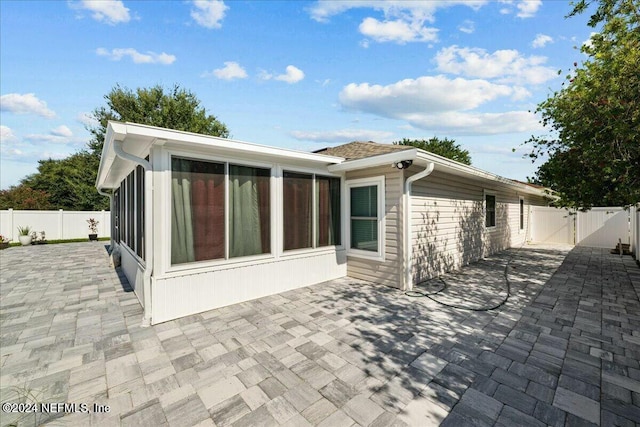 rear view of house with a sunroom and a patio