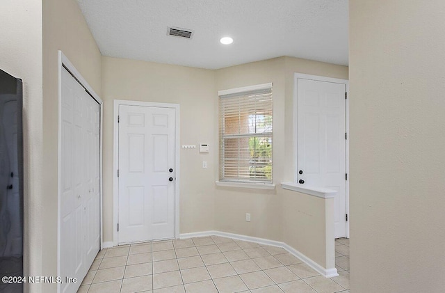 entryway featuring light tile patterned floors and a textured ceiling