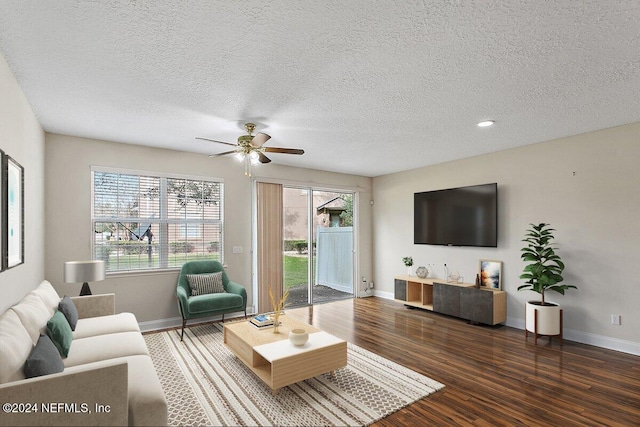 living room featuring a textured ceiling, dark hardwood / wood-style flooring, and a healthy amount of sunlight