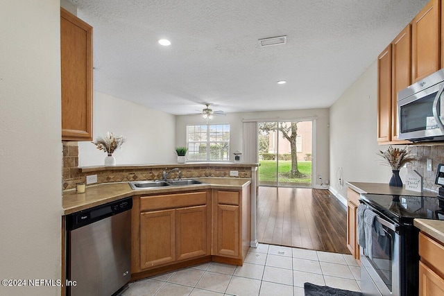 kitchen featuring ceiling fan, sink, kitchen peninsula, appliances with stainless steel finishes, and light wood-type flooring