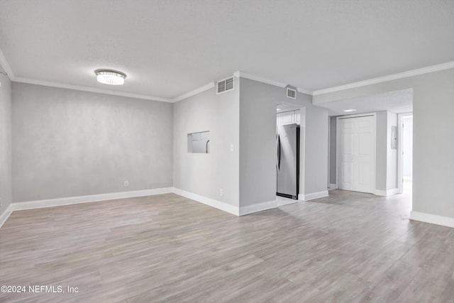 unfurnished room featuring a textured ceiling, light wood-type flooring, and ornamental molding