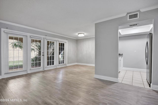 spare room with light hardwood / wood-style floors, a textured ceiling, and ornamental molding