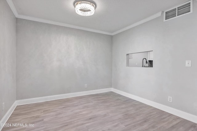 spare room featuring a textured ceiling, light wood-type flooring, and crown molding