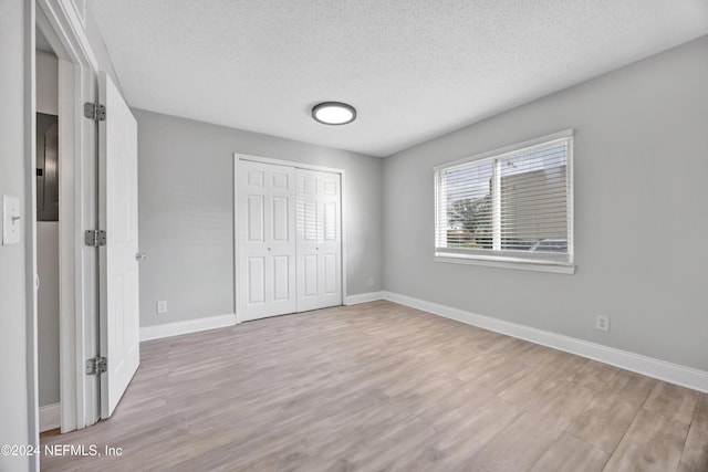 unfurnished bedroom featuring a closet, light hardwood / wood-style flooring, and a textured ceiling