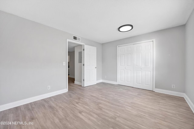 unfurnished bedroom with light wood-type flooring and a closet