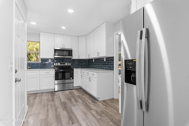 kitchen featuring tasteful backsplash, white cabinetry, light hardwood / wood-style flooring, and stainless steel appliances