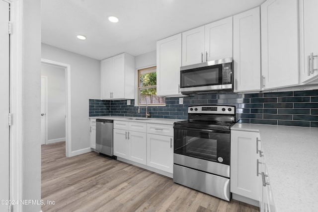 kitchen featuring sink, backsplash, light hardwood / wood-style floors, white cabinets, and appliances with stainless steel finishes