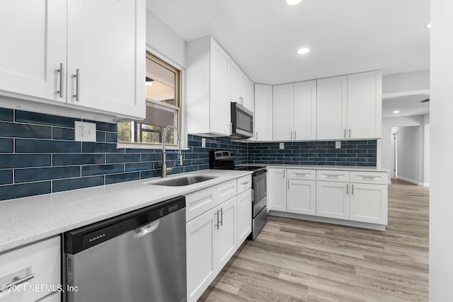 kitchen with light stone countertops, appliances with stainless steel finishes, sink, light hardwood / wood-style flooring, and white cabinets